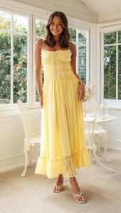 Détail de robe longue plissée jaune avec lacets délicats sur la poitrine et fines bretelles