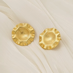 Macro shot of 18k gold plated round earrings with textured spiral wave surface