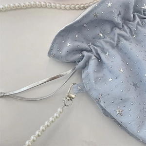 Detail of light blue drawstring canvas bag with silver stars and pearl chain strap