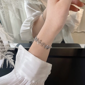 Close-up of a silver musical note bracelet featuring treble clef charms on a woman's wrist