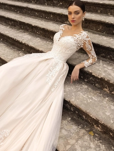 Detailed view of sheer V-neck long sleeves with intricate floral lace on a white bridal gown