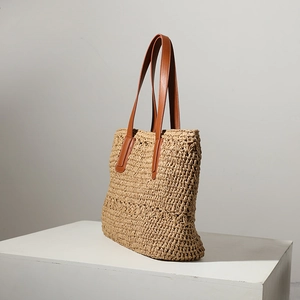 Minimalist beige woven straw tote bag with brown leather handles for beach vacation