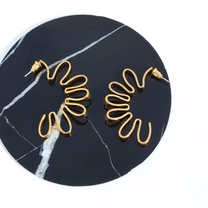 Creative wavy golden petal-shaped earrings with metallic texture on black marble base