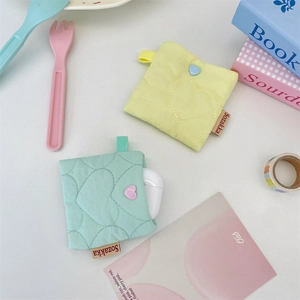 Close-up of heart-quilted soft fabric earphone pouches in yellow and mint green