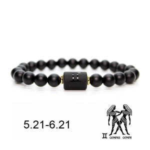Macro detail of matte black Gemini zodiac bead bracelet with gold metal spacers