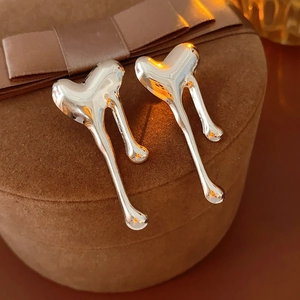 Macro shot of liquid metal heart earrings with a high-polish silver finish on velvet box