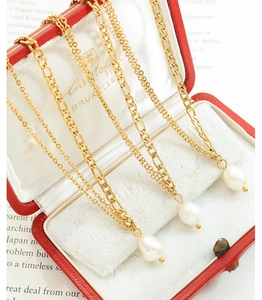 Detailed macro of gold Figaro chains and teardrop Baroque pearls on a vintage jewelry box