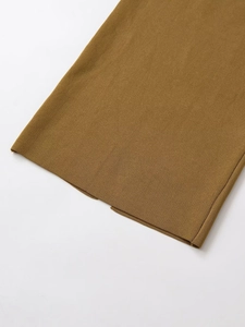 Détail de l'ourlet de la jupe en tricot jaune gingembre avec fente et texture