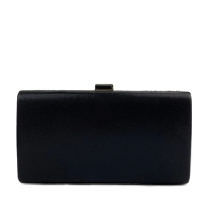 Detailed close-up of a black evening clutch bag with refined texture and metal clasp