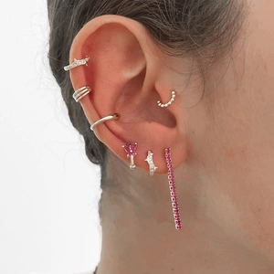 Detailed view of silver star hoop earrings and pink crystal butterfly studs on ear