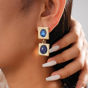 Nahaufnahme der Vintage-Goldohrringe mit blauen Kristallen und Steinen am Modell