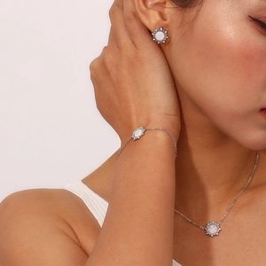 Polished silver stainless steel jewelry set with white opal sunburst charms on a model