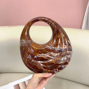 Handheld view of acrylic evening bag featuring unique brown amber tortoise texture