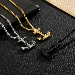 Detailed close-up of men's anchor pendants in silver, gold, and black on black leather