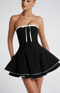 Detail of a black tube dress featuring white bow tie and layered ruffled hemline