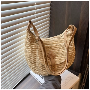 Minimalist beige straw crescent shoulder bag with brown leather strap and shield detail