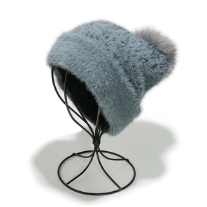 Detail of grey-blue knit hat with plush faux fur texture and large pompom on top
