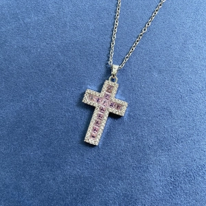 Collana a croce in argento con pietre rosa e diamanti su sfondo di velluto blu