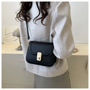Detail view of black matte leather crossbody bag with golden rectangular turn-lock