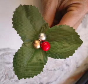 Detailed view of artificial Christmas branch with green leaves and metallic color berries