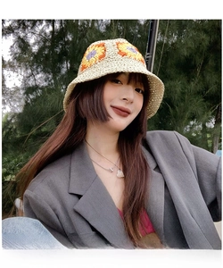 Detail of hand-woven cream bucket hat with colorful crochet flower patterns