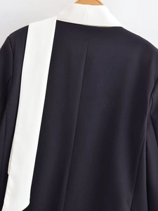 Detailed view of black blazer with contrast white trim on collar and shoulder seam