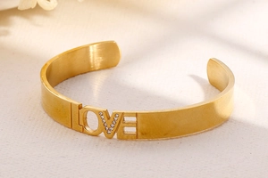 Macro shot of gold LOVE bangle with sparkling white rhinestones and brushed metal texture