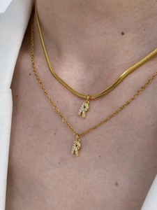 Detail of layered gold initial R necklaces featuring a snake chain and zircon pendant