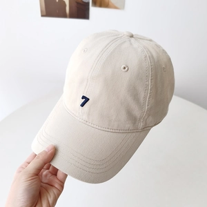 Beige cotton baseball cap with blue number 7 embroidery and curved brim in hand display