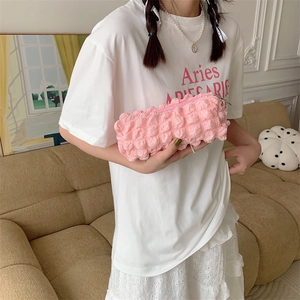 Close-up of pink bubble texture pencil case held by a model in a cozy indoor setting