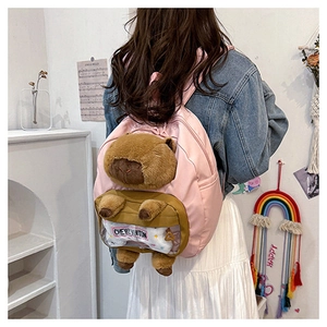 Detail of pink backpack featuring a plush capybara doll and transparent PVC pocket detail