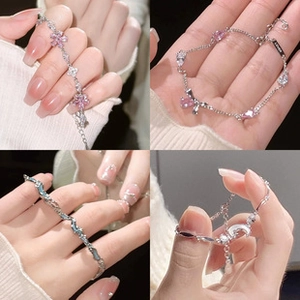 Close-up of silver bracelets featuring floral gems, moon charms, and blue wave patterns