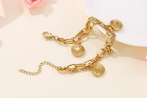 Close-up of golden titanium steel double-layer bracelet with sunray coin charm
