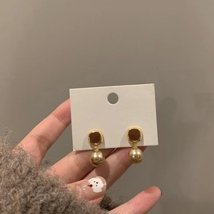 Detail of vintage gold square earrings with champagne pearl charms held by hand