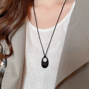 Gros plan du collier pendentif ovale noir avec cordon tressé sur mannequin en détail