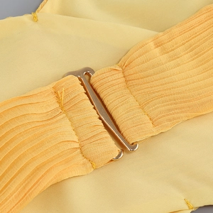 Détail du tissu plissé jaune avec boucle en métal doré réglable sur une robe