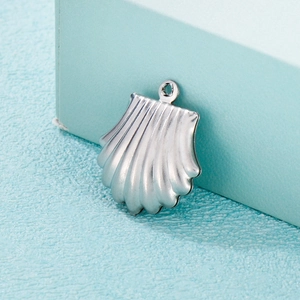 Minimalist silver stainless steel shell pendant accessory on a soft blue textured surface