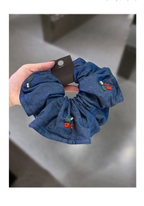 Detail of dark blue denim scrunchie with cherry embroidery and white faux pearls