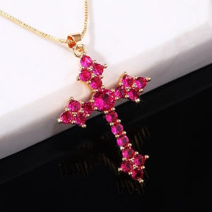 Elegant gold-tone cross necklace set with pink crystal zircon on marble background