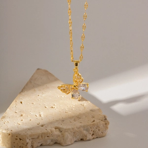 Détail du collier papillon en acier doré 18K avec zircon sur pierre beige