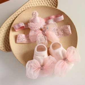 Detailed view of a pink baby headband and sock set with lace mesh bows on ceramic trays