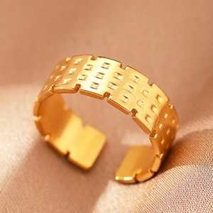 Macro view of gold stainless steel open ring with geometric square brick texture