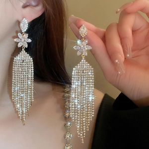 Macro detail of long floral tassel earrings with sparkling crystals in silver plating