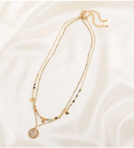 Detail of layered gold-plated necklace with bohemian beads and natural stone pendant