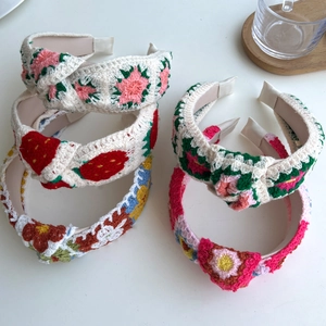 Detail of five handmade crochet headbands with colorful floral and strawberry patterns