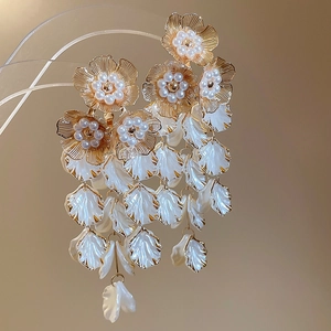 Macro detail of vintage floral tassel earrings with gold metal petals and pearl accents