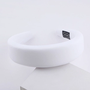 White padded milk silk sponge headband with handmade label on minimalist stand