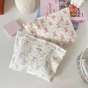 Close-up of canvas makeup bags with floral bow prints and metal zipper detail