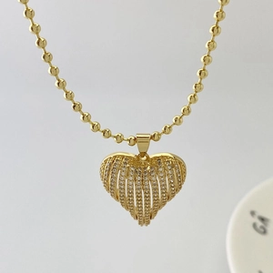 Detail of a gold heart pendant with hollow striped texture and pave cubic zirconia stones