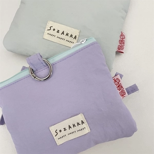 Dettaglio di porta carte in tessuto con cerniera e fiocco in viola e grigio
